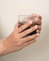 hand är innehav en glas av kaffe med ices på en vit isolerat bakgrund foto