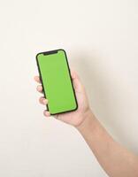 hand är innehav en telefon med grön skärm på en vit isolerat bakgrund foto