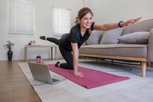 ung asiatisk sportig kondition kvinna tränare do öva video uppkopplad Träning yoga bärbar dator i levande rum på Hem foto