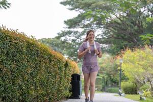 ung skön asiatisk kvinna joggning på de parkera i de morgon, hälsa och övning begrepp. foto