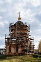 restaurering av de gammal byggnad, ortodox kyrka under rekonstruktion, byggnadsställningar tillverkad av trä, restaurering av de kristen helgedom, de tempel av Gud. foto