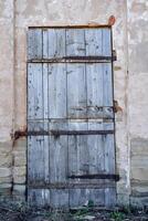 de gammal trä- dörr är stängd med bultar. de ingång till de byggnad av ett gammal strukturera, en grå trä- duk stänger de ingång till de hus. foto