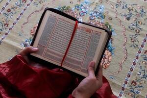 hand av en muslim kvinna innehav de quran med indonesiska översättning foto