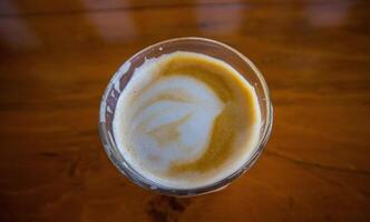varm latte med latte konst i trä- bakgrund foto
