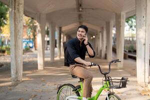 eco vänlig, Lycklig livsstil asiatisk ung affärsman rida cykel gå till kontor arbete på stad gata med cykel i morgon- foto