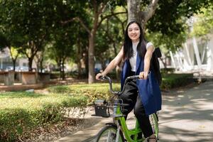 asiatisk affärskvinna i cykel gå till arbete på kontor. cykel pendling, Lycklig affärskvinna använder sig av eco transport, begrepp av eco livsstil foto