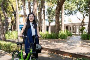 eco vänlig, Lycklig livsstil asiatisk skön ung affärskvinna ridning cykel gå till kontor arbete på stad gata med cykel i morgon- foto