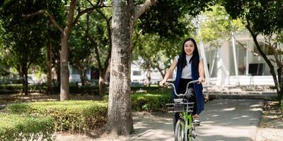 eco vänlig, Lycklig livsstil asiatisk skön ung affärskvinna ridning cykel gå till kontor arbete på stad gata med cykel i morgon- foto