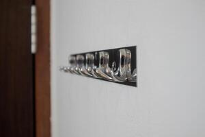 metall eller rostfri stål galge på vit vägg. silver- krokar Bakom de dörr. foto