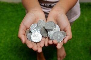 indonesiska mynt i händer. asiatisk barn innehav indonesiska mynt pengar. sparande pengar och investering begrepp. foto