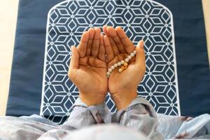 en muslim kvinna bär moslem kläder med hijab kallad mukena och höjning henne händer för bön- foto