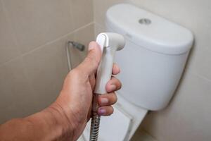 hand innehav bidé dusch i en toalett foto