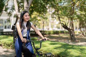 asiatisk affärskvinna i cykel gå till arbete på kontor. cykel pendling, Lycklig affärskvinna använder sig av eco transport, begrepp av eco livsstil foto