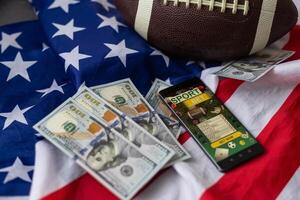 rugby boll och dollar med USA flagga och smartphone slå vad foto