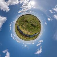 grön liten planet i blå himmel med vackra moln. transformation av sfäriskt panorama 360 grader. sfärisk abstrakt flygfoto. utrymmets krökning. foto