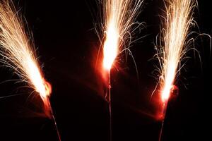 lång exponering tre sparklers brinnande ljus mot mörk foto