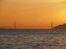 avlägsen se av gyllene Port bro med orange solnedgång himmel foto