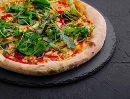 pizza med arugula på svart styrelse foto