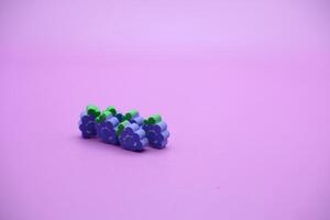 lila bakgrund med druva leksaker. druvformad suddgummi isolerat på lila bakgrund. foto
