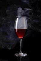 en glas av vin med rök kommande ut av den foto