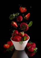 jordgubbar faller in i en skål foto