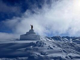 en man stående på topp av en snö täckt berg foto