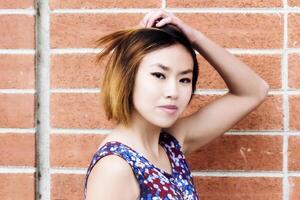 attraktiv asiatisk amerikan kvinna porträtt med tegel vägg foto