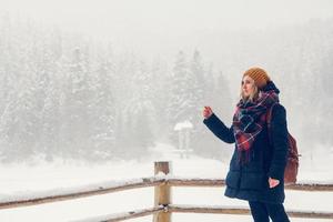 porträtt av en vacker flicka med en ryggsäck på en bakgrund av snötäckt skog foto