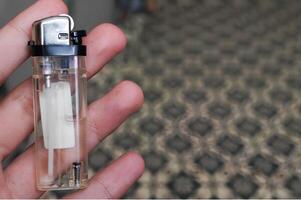 hand innehav en transparent gas lättare inomhus foto