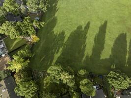 grön fält med träd skuggor och bostads- hus - antenn se foto