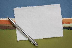 små ark av tom vit khadi trasa papper från Indien mot abstrakt landskap med en penna foto