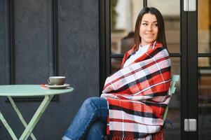 porträtt av ung skön kvinna Sammanträde i en Kafé utomhus- dricka kaffe foto