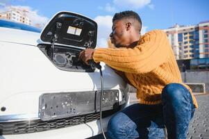 afrikansk amerikan man laddning hans elektrisk bil. foto