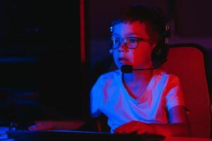 liten pojke spelar video spel i de mörk rum foto