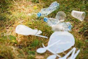 en lugg av plast på grön gräs, en problem i de naturlig miljö, förorening av natur är inte sönderfallande plast. skydd av natur. foto