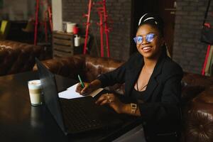 ung afrikansk amerikan kvinna lokaliserings på Kafé arbetssätt på bärbar dator foto