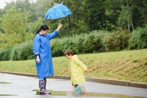 mor med son gående i parkera i de regn bär sudd stövlar foto