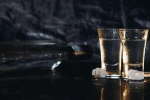 vodka i skott glasögon på mörk bakgrund foto