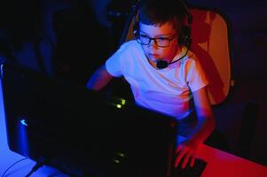 professionell gamer spelar video spel på hans dator. han är deltar i uppkopplad cyber spel turnering eller i internet Kafé. han bär glasögon och samtal in i mikrofon. foto