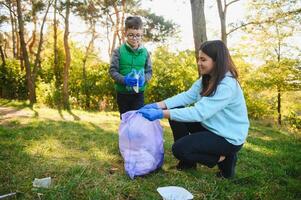 kvinna volontär- och liten pojke plockning upp de plast sopor foto