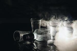 närbild se av flaska av vodka med glasögon stående på is på svart. foto