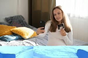 graviditet, moderskap, teknologi, människor och förväntan begrepp - Lycklig gravid kvinna med smartphone vinka henne hand, kommunicerar på en video ring upp foto