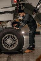 manlig mekaniker reparation flygplan hjul i hangar foto