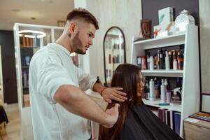 professionell manlig frisör pensling lång brun hår av kvinna klient, framställning frisyr på skönhet salong foto