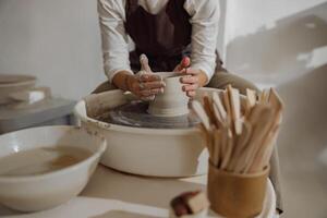kvinna krukmakare i förkläde framställning form av lera vas på spinning krukmakeri verktyg i keramisk verkstad foto
