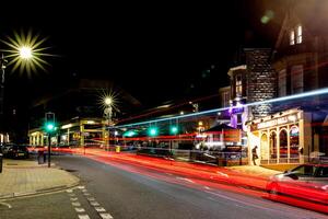 natt stadsbild med ljus spår från rör på sig fordon på en livliga gata, visa upp urban nattliv och rörelse i harrogate, norr yorkshire, Storbritannien. foto