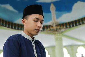 porträtt av religiös asiatisk man i muslim skjorta bön- och håller på med salat eller sholat i moské foto