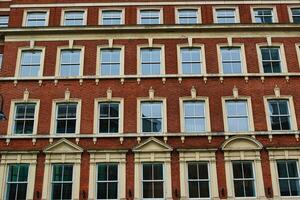 Fasad av en klassisk röd tegel byggnad med symmetrisk fönster mot en klar himmel i leeds, Storbritannien. foto