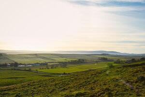 lugn landskap med rullande kullar och frodig grönska under en mjuk solnedgång himmel på platan glipa, Northumberland, Storbritannien. foto