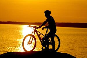 silhuett av en sportig cyklist i hjälm på en cykel. aktiva livsstil begrepp. foto